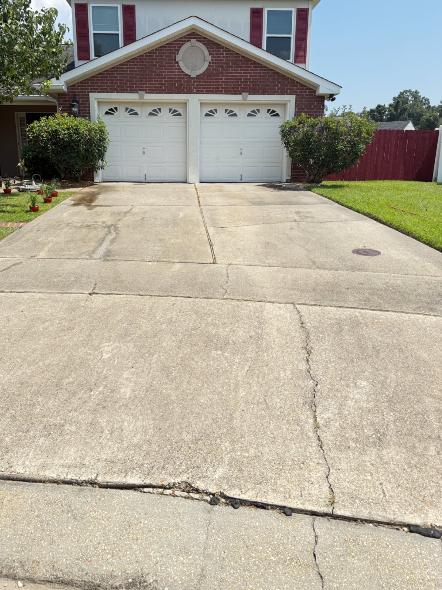 Dirty concrete driveway with oil stains and discoloration before pressure washing in Metairie, Louisiana.