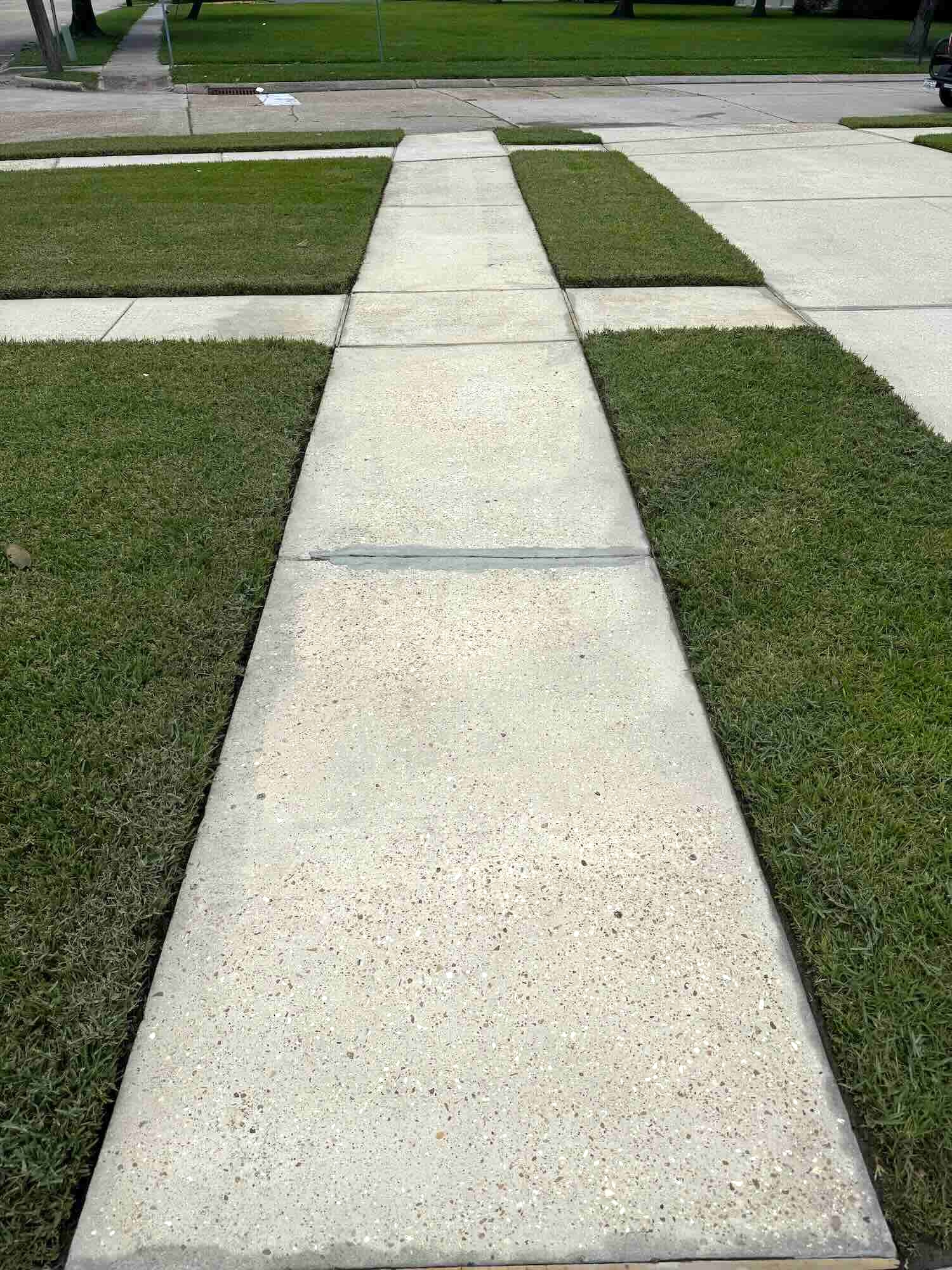 Restored and spotless sidewalk after professional pressure washing service in New Orleans by Love Bug Pressure Washing.